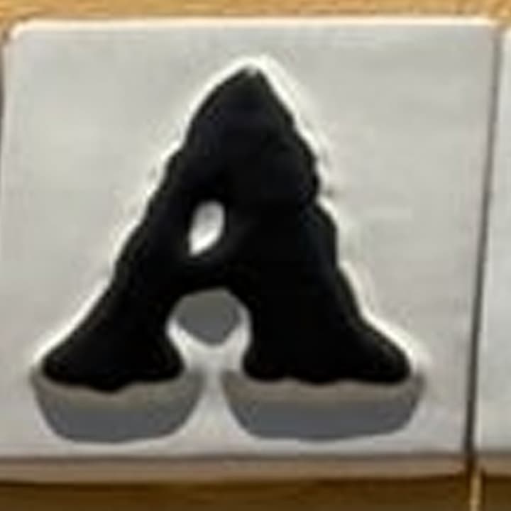 Perspective-rectified source tile showing a hand-painted ceramic letter A